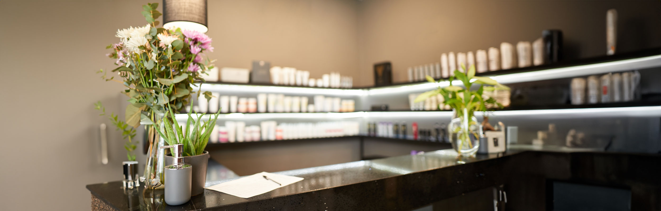 Empfangstresen eines Kosmetikinstituts mit Blumen, Pflanzen und BABOR Pflegeprodukten